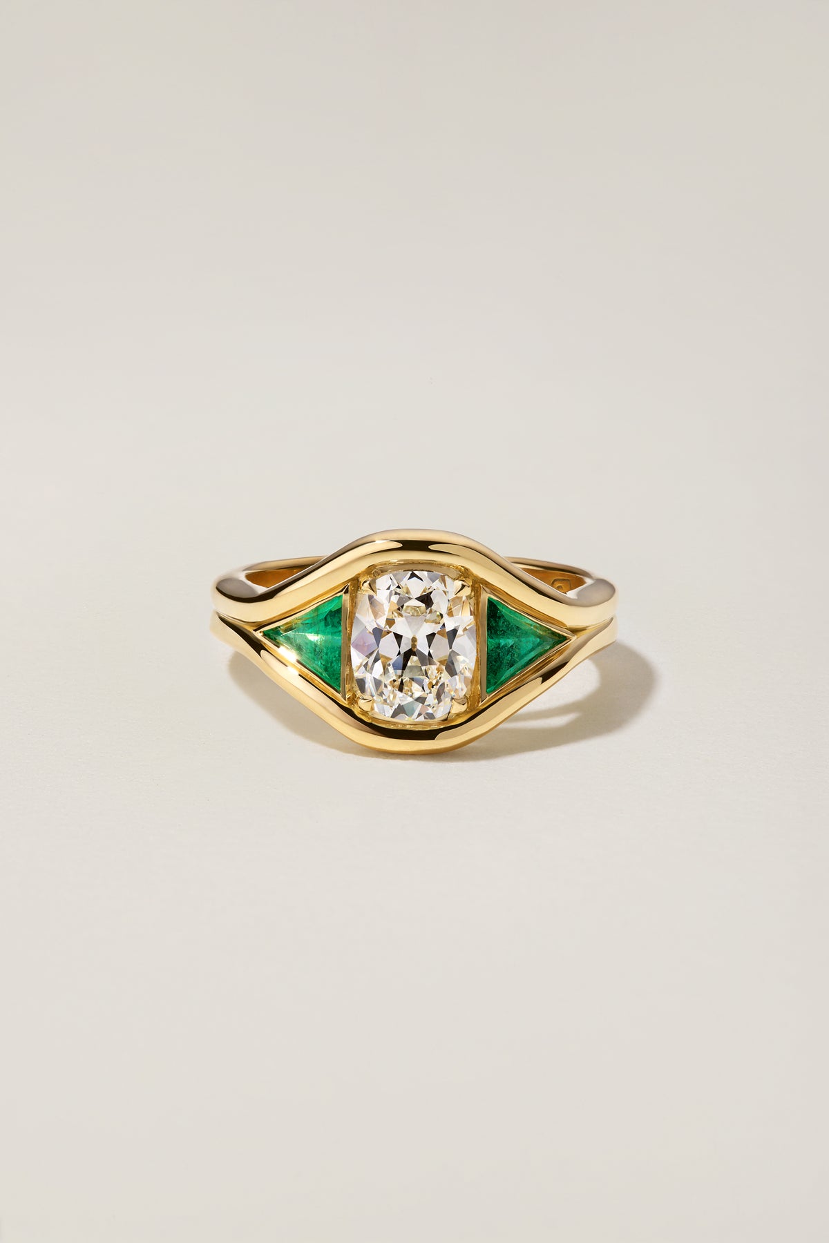 Emmy Ring, a 1.27 carat old mine cut diamond with trillion cut emerald side stones in 18k yellow gold