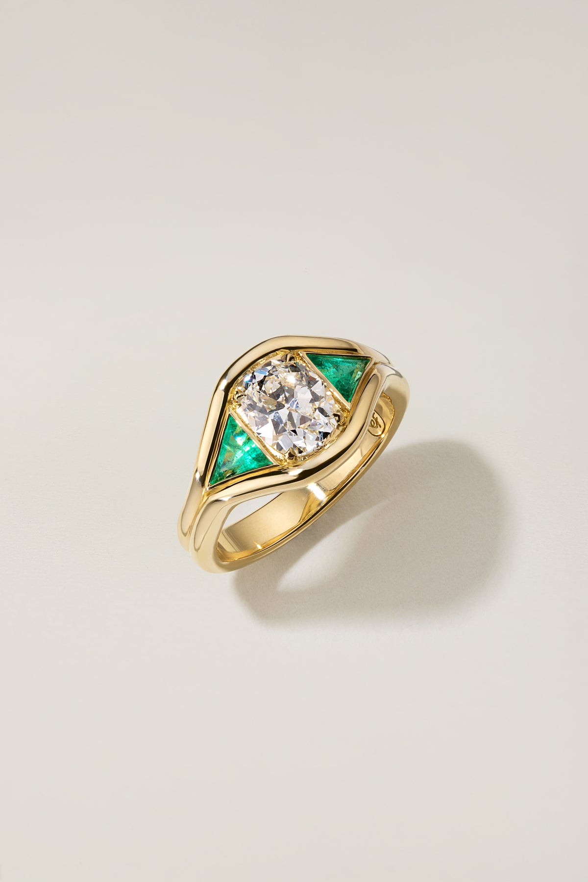 Emmy Ring at an angle, with the triangular emeralds fitted into the curves of the gold