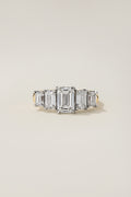 Nicci five-stone ring from the front: an emerald cut center diamond with four graduated emerald cut side stones in platinum, on an 18k yellow gold shank