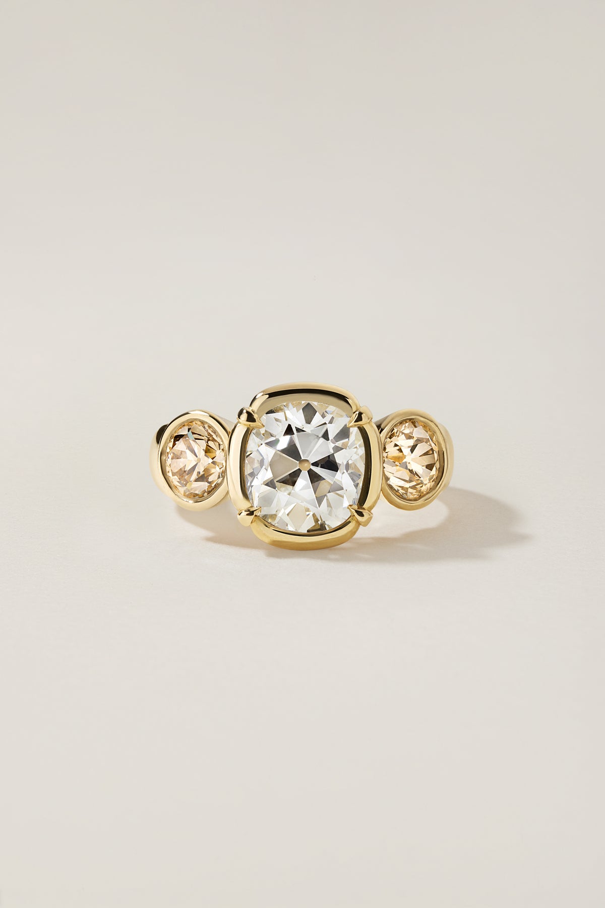 Rosa Ring, a 2.65 carat old mine cut diamond with two bezel set champagne diamond side stones
